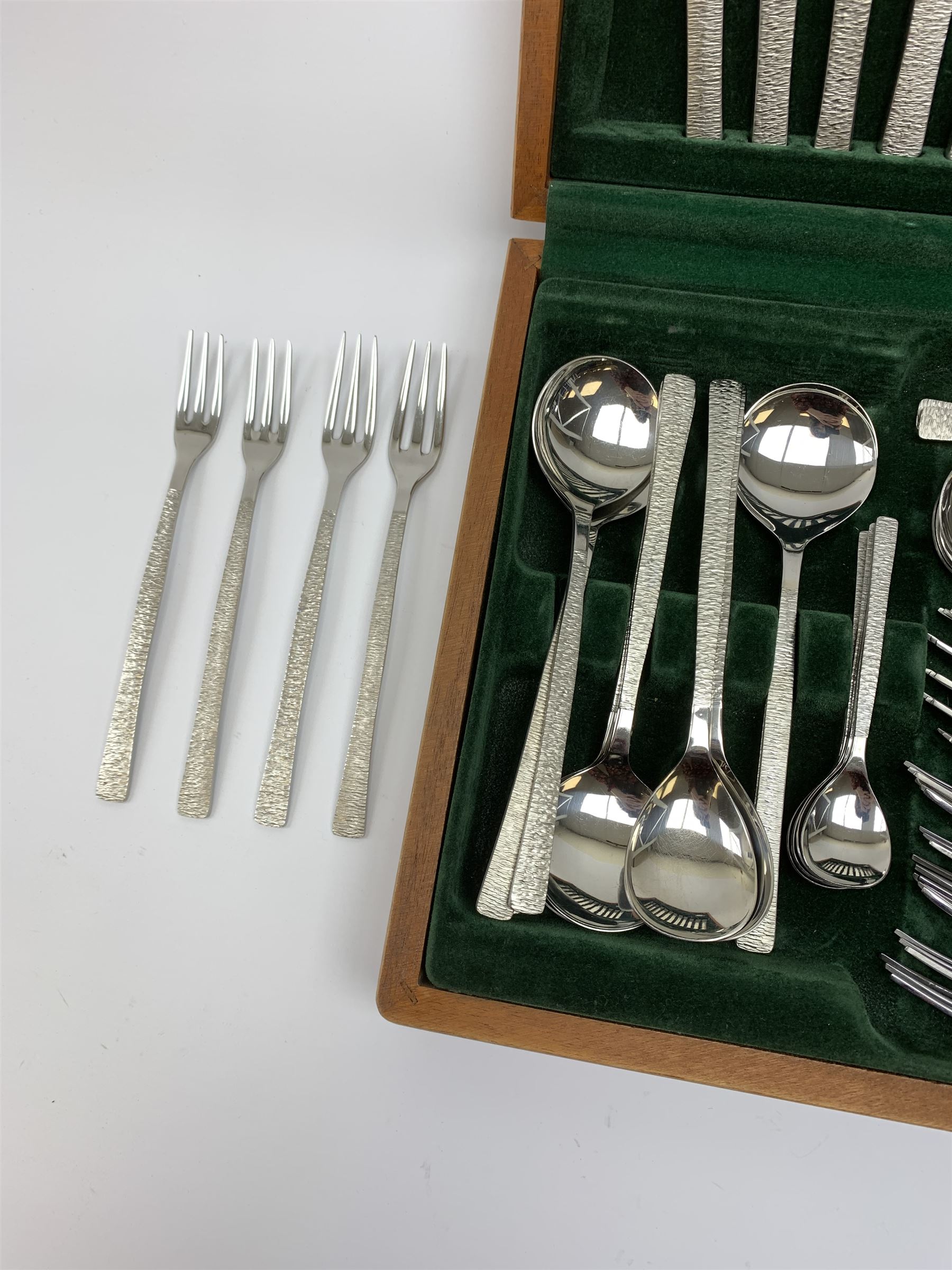 A canteen of bark effect stainless steel cutlery by Gerald Benney for Viners Studio, in a teak case. 