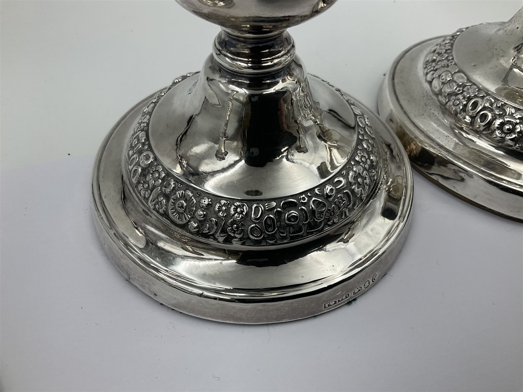 Four George III silver candlesticks, each upon knopped stem and weighted circular stepped foot, the foot and removable sconce repousse decorated with a band of flower heads, hallmarked to sconce and foot Thomas & John Settle, Sheffield 1820, H17.5cm