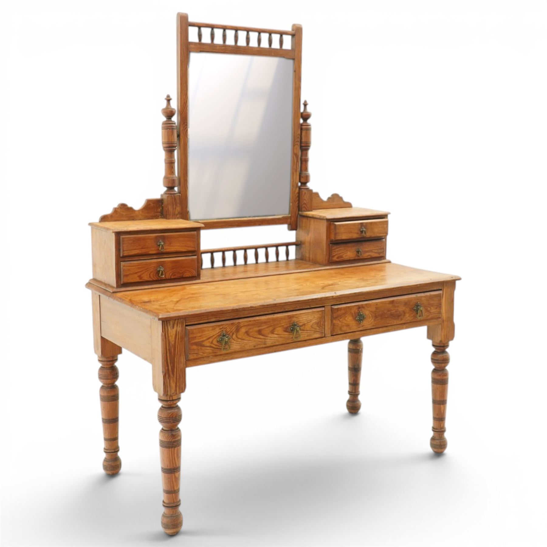 Victorian stripped pine dressing table, rectangular top over two drawers with brass handles, the raised back fitted with adjustable rectangular mirror, spindle gallery flanked by two short jewellery drawers either side, on turned legs