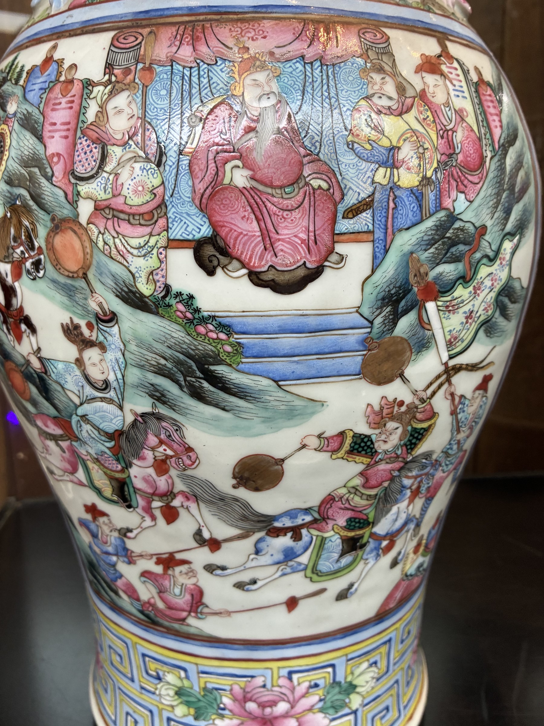 Large pair of 19th century Cantonese famille rose vases, each painted with various courtly scenes, including a display of warriors fighting on horseback before an official and his attendants, double Buddhist lion handles and applied at the shoulders with chilong, the lower band painted with Greek key motif, H58cm (2)