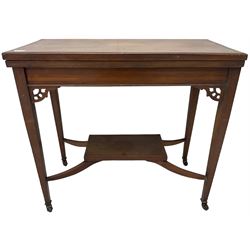 Edwardian inlaid mahogany games table, the rectangular fold-over swivel top decorated with central shell motif inlay and ebony stringing, raised on tapering supports united by shaped X-stretcher and undertier