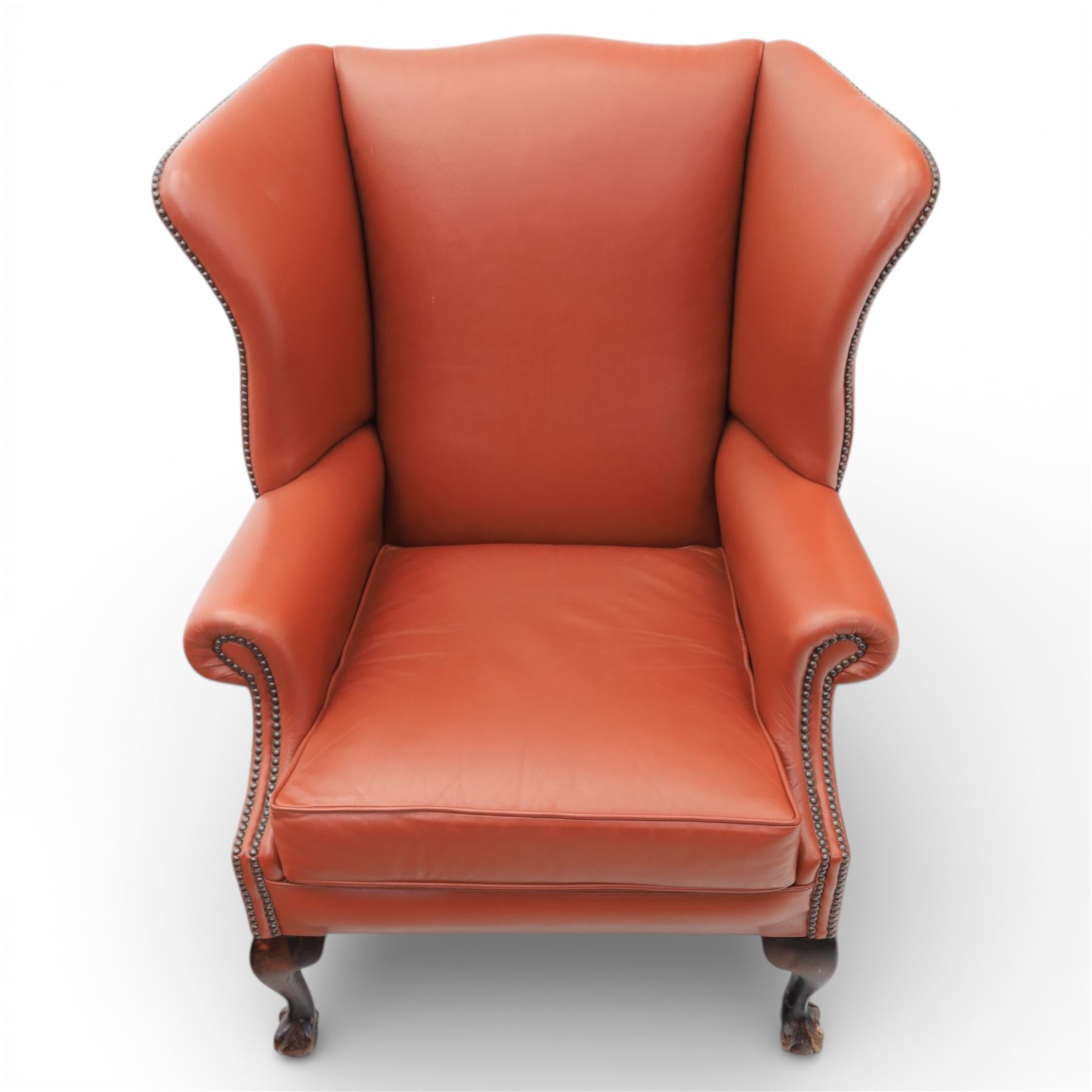 Georgian design red leather wingback armchair, with shaped back and scrolled arms, and close brass studded trim, upon cabriole front legs with claw and ball feet