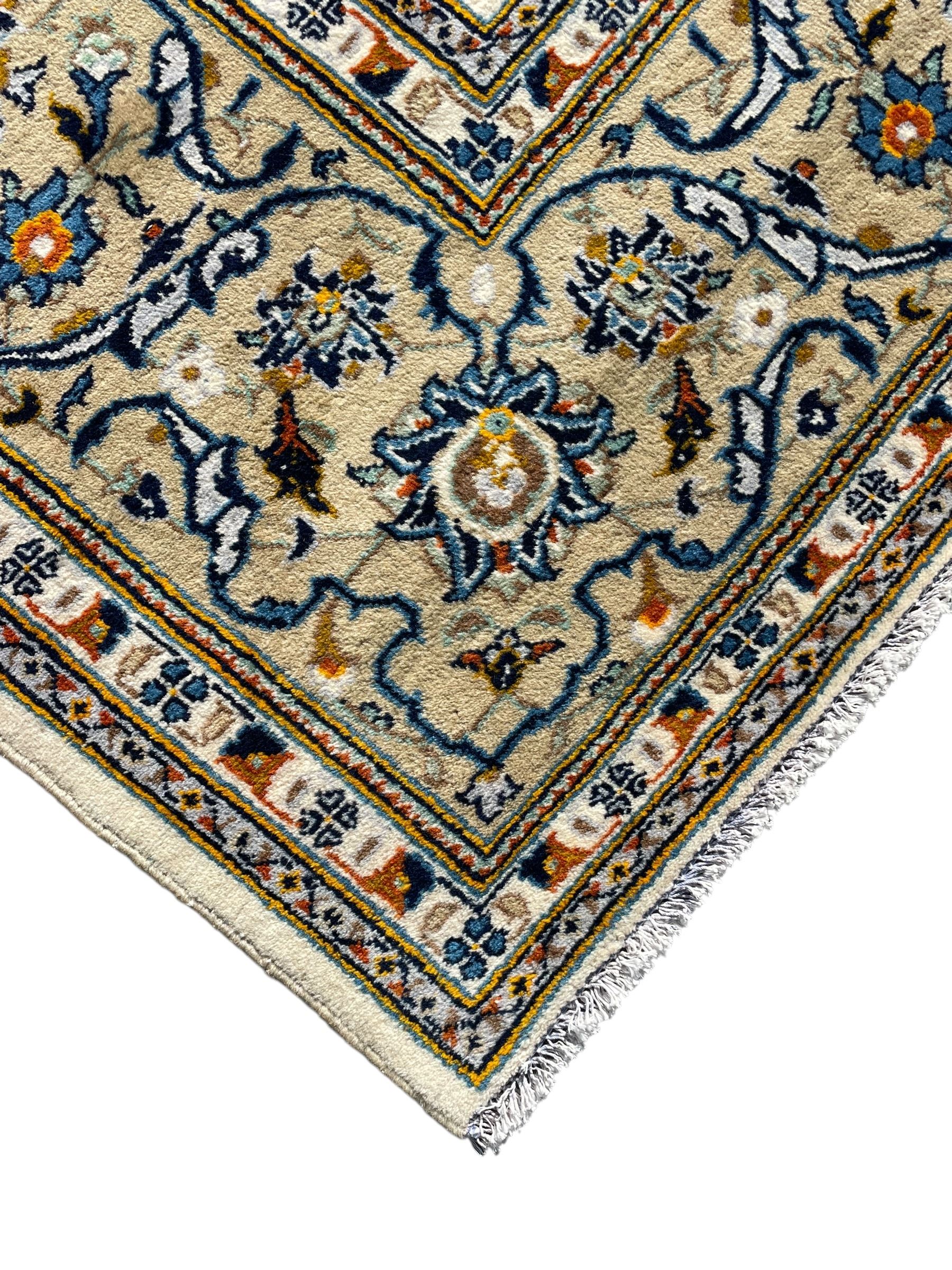 Persian Kashan ivory ground carpet, overall floral design, the field decorated with scrolling and interlaced leafy branches interspersed with palmettes, scrolling border decorated with stylised plant motifs, within floral pattern guard stripes 