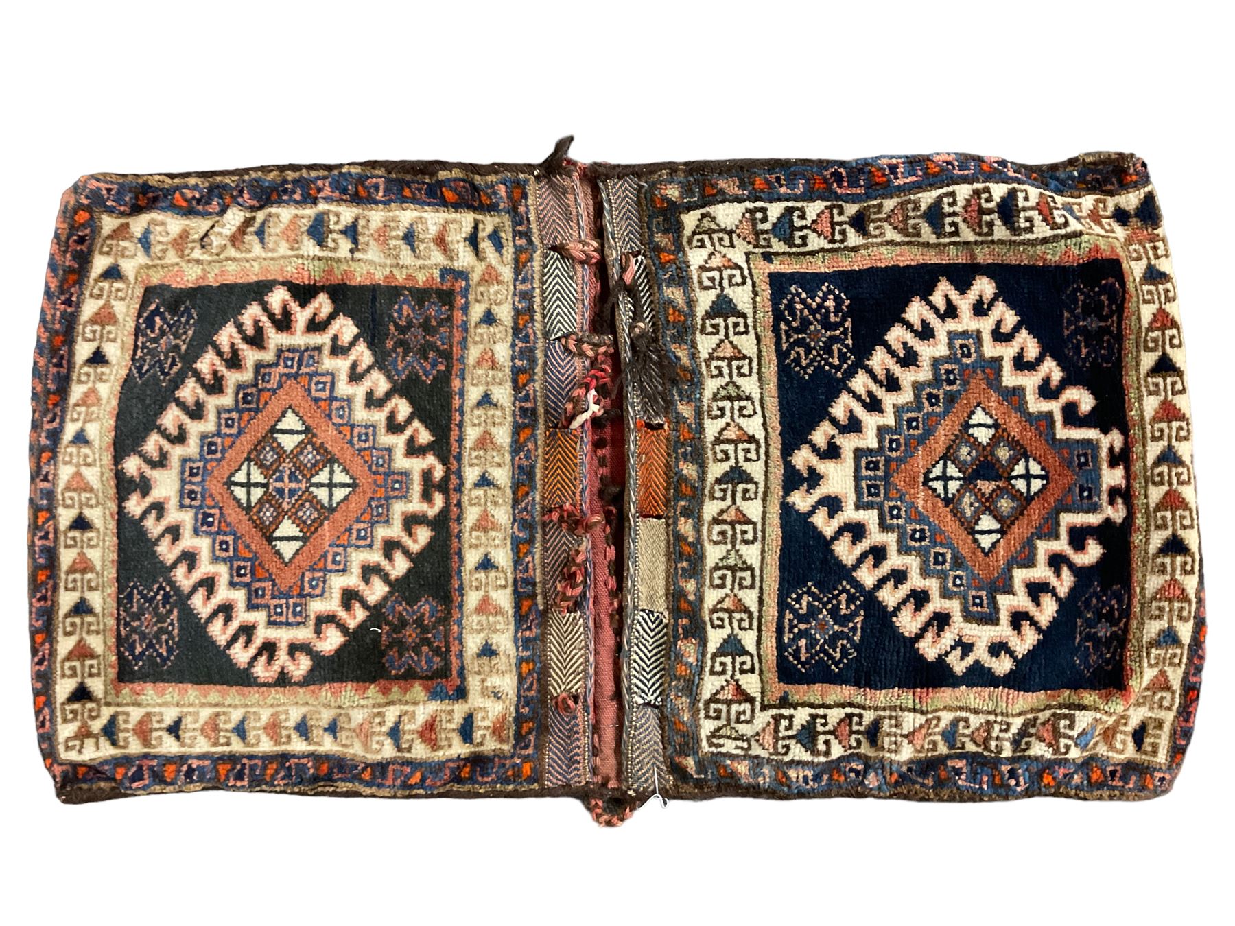 Antique Persian red ground saddle bag, decorated with all-over Boteh motifs, geometric patterned border (127cm x 68cm); Persian indigo ground saddle bag, decorated with two geometric ivory lozenges (113cm x 62cm); Persian red ground saddle bag decorated with lozenges and multi-band border (110cm x 65cm) 