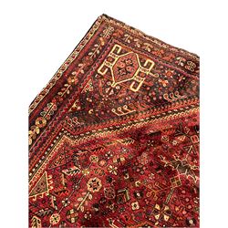 Persian Qashqai red ground rug, the main field decorated profusely with small stylised motifs, central lozenge medallion, multi-band border decorated with trailing foliate and flower head motifs 