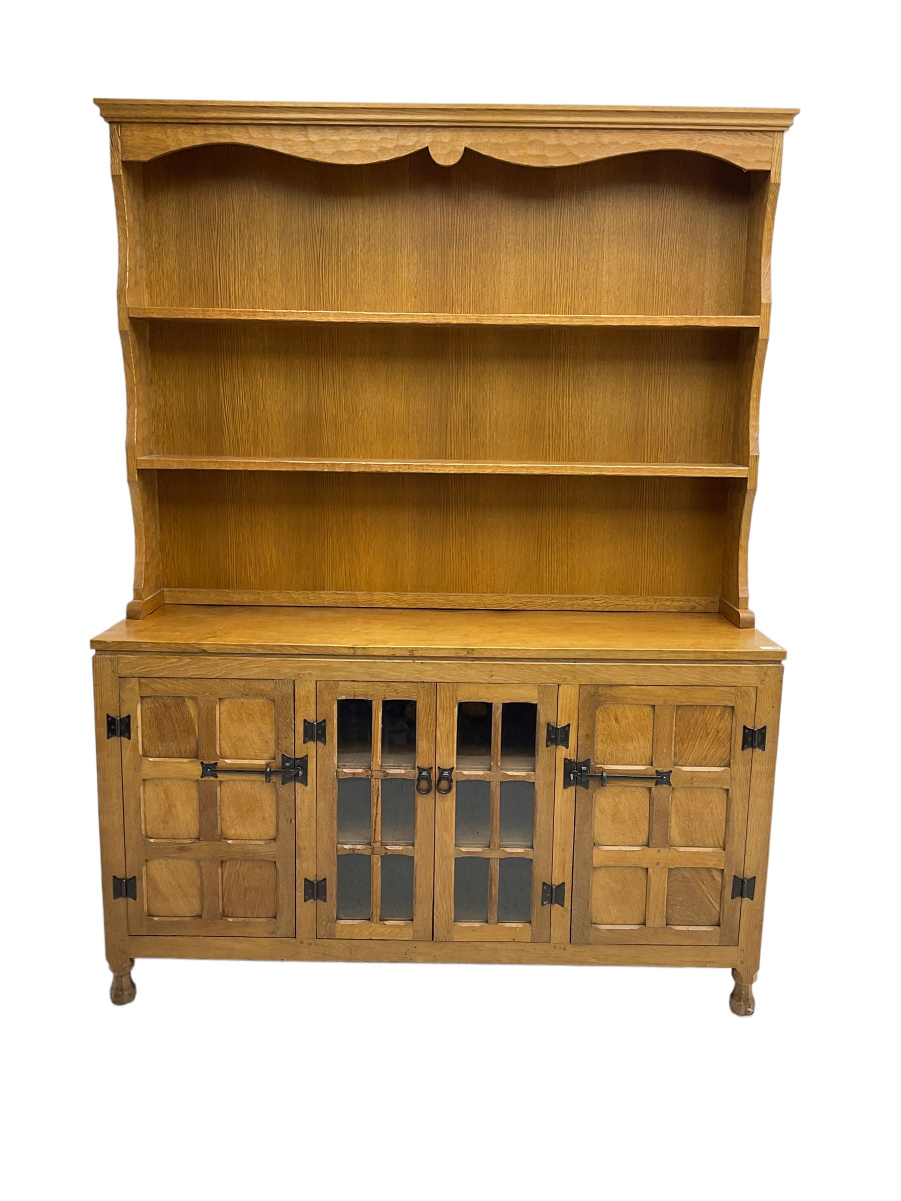 Yorkshire oak - adzed oak dresser, the rack with projecting cornice over shaped frieze and two shelves, the dresser fitted with central glazed double cupboard flanked by two panelled single cupboards, panelled sides