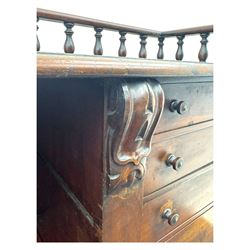 Large Victorian mahogany Registry/Dickens’ desk, spindle gallery top, one side with five small drawers and the other with blind cupboard drawer, revealing pigeon holes with scroll carved locking side bars on either side, above a hinged and leathered writing slope with three drawers and pigeon holes underneath, above a central locking drawer with key, the pedestals each with four drawers and  turned knob handles, separates into four parts for transport