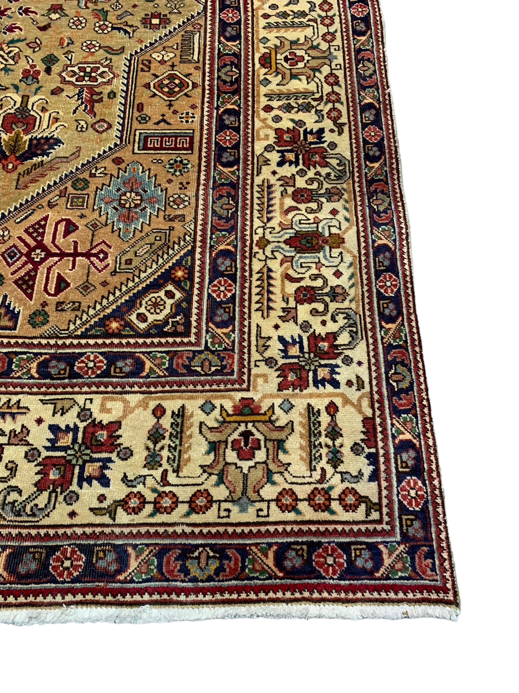 Persian Azarbaijan golden ground carpet, the shaped crimson ground medallion decorated with geometric motifs, the field profusely decorated with stylised plant and flower head motifs, repeating border with guard bands 