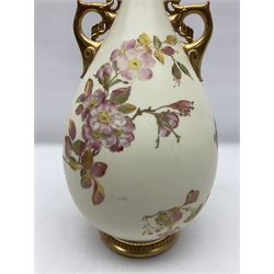 Royal Worcester, blush ivory twin handled vase, the bulbous body decorated with hand painted flowers, the tall tapering neck with foliate pierced detail and gilt finish, with printed mark beneath 