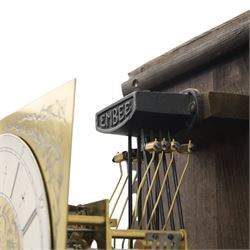 Early 20th century oak longcase clock, square brass dial with engraved foliate spandrels and centre, silvered Roman chapter ring with Arabic minute track, Westminster chime movement, the plain case with glazed arched trunk door and moulded plinth