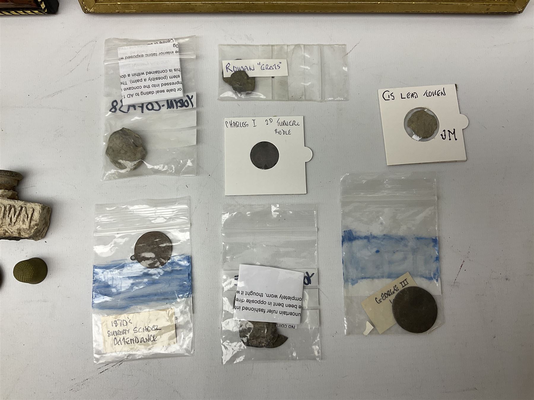 Collection of metal detecting finds, most contained within display frames and labelled, some loose, to include musket balls, bill hook, axe fragment, hubcaps, shell cases, regimental badges, coins, etc. 