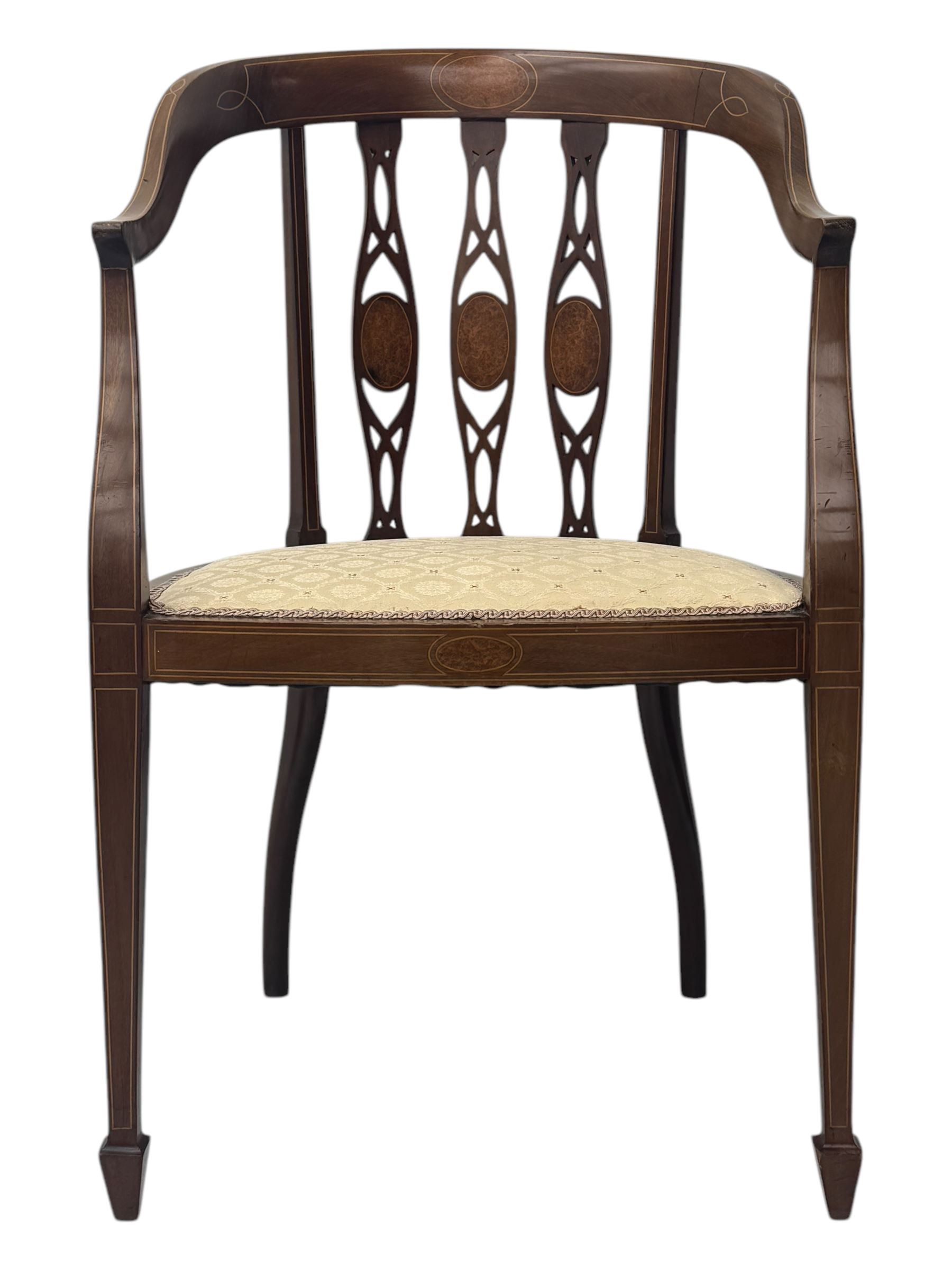 Pair of Edwardian mahogany tub chairs, curved top rail inlaid with oval marquetry panels, the backs with a pierced, elongated splat design featuring a central oval motif, the seats upholstered in cream fabric, on square tapering supports with spade feet