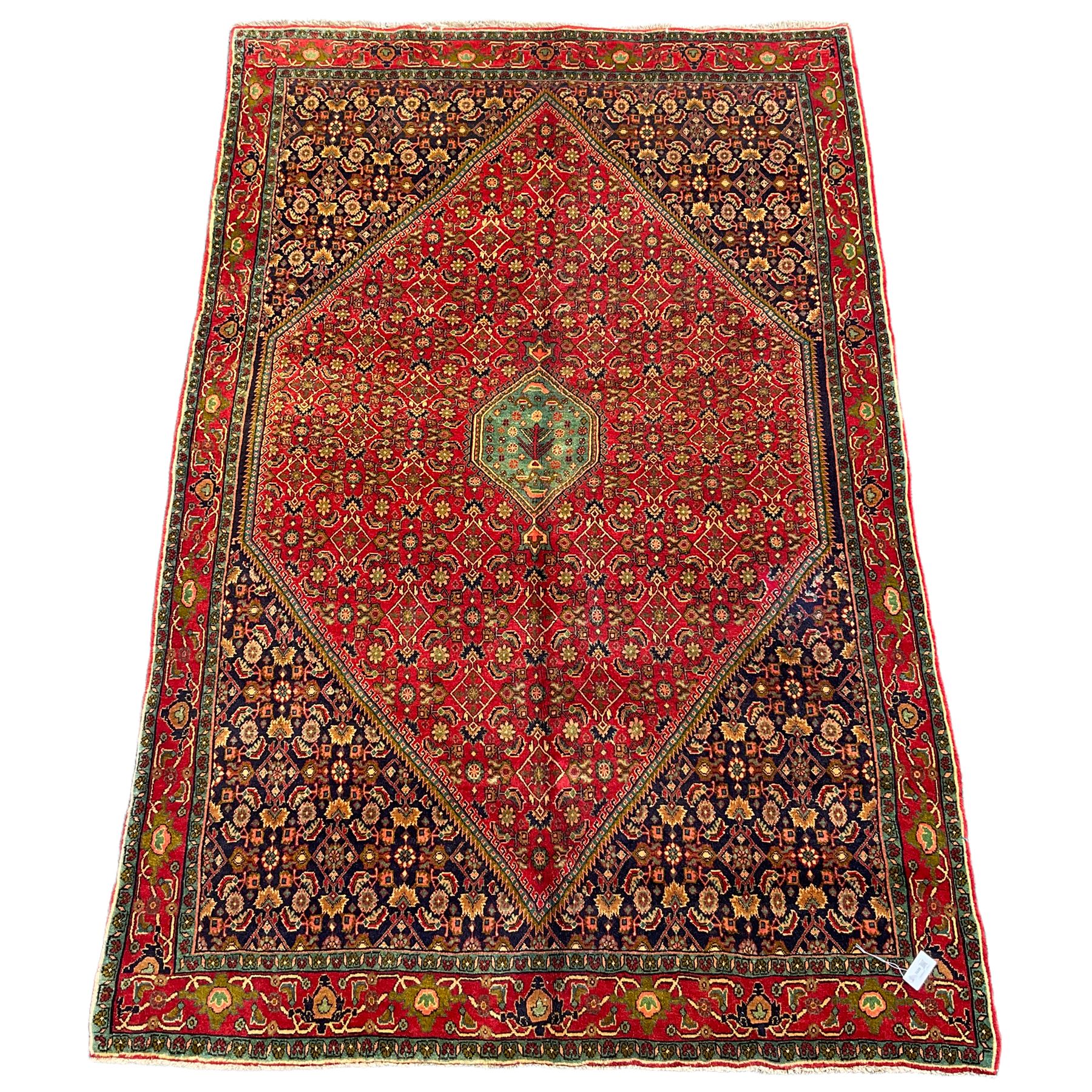 Persian Bijar red and blue ground rug, central panel decorated with tree of life and flower head motifs, decorated all-over with Herati motifs, triple band band border decorated with stylised plant motifs