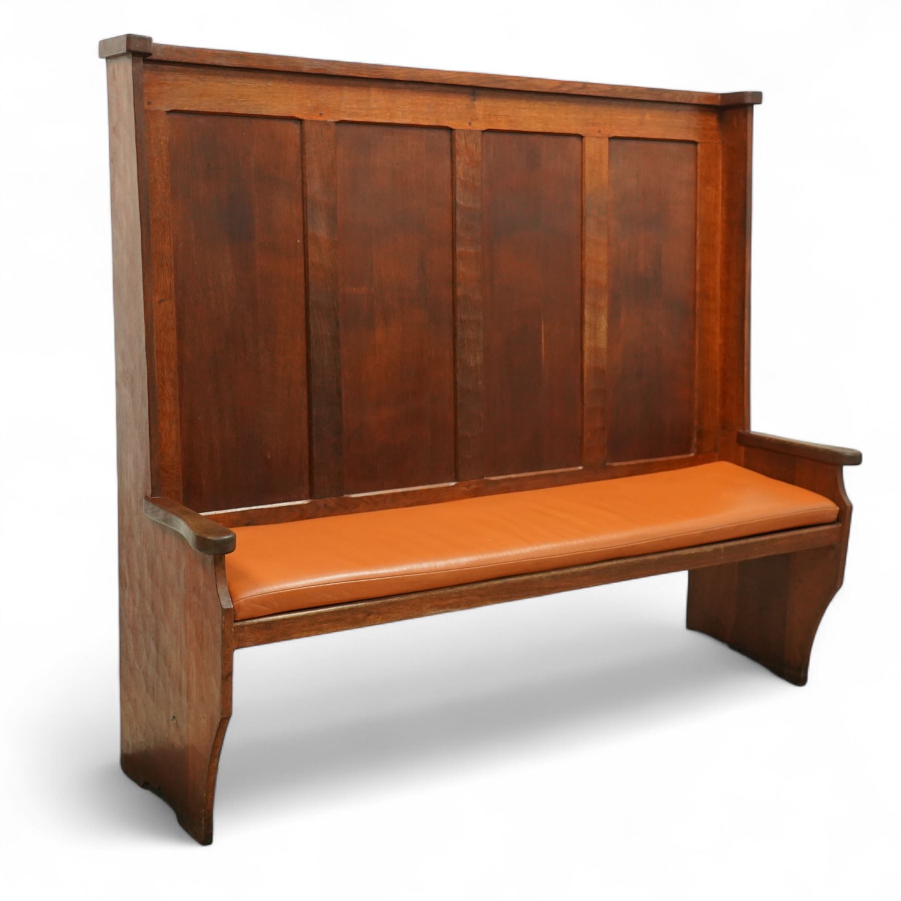 Sid Pollard of Thirsk – late 20th century adzed oak settle, tall panelled back with projecting top rail, shaped arms and tan upholstered drop-in seat, raised on chamfered end supports