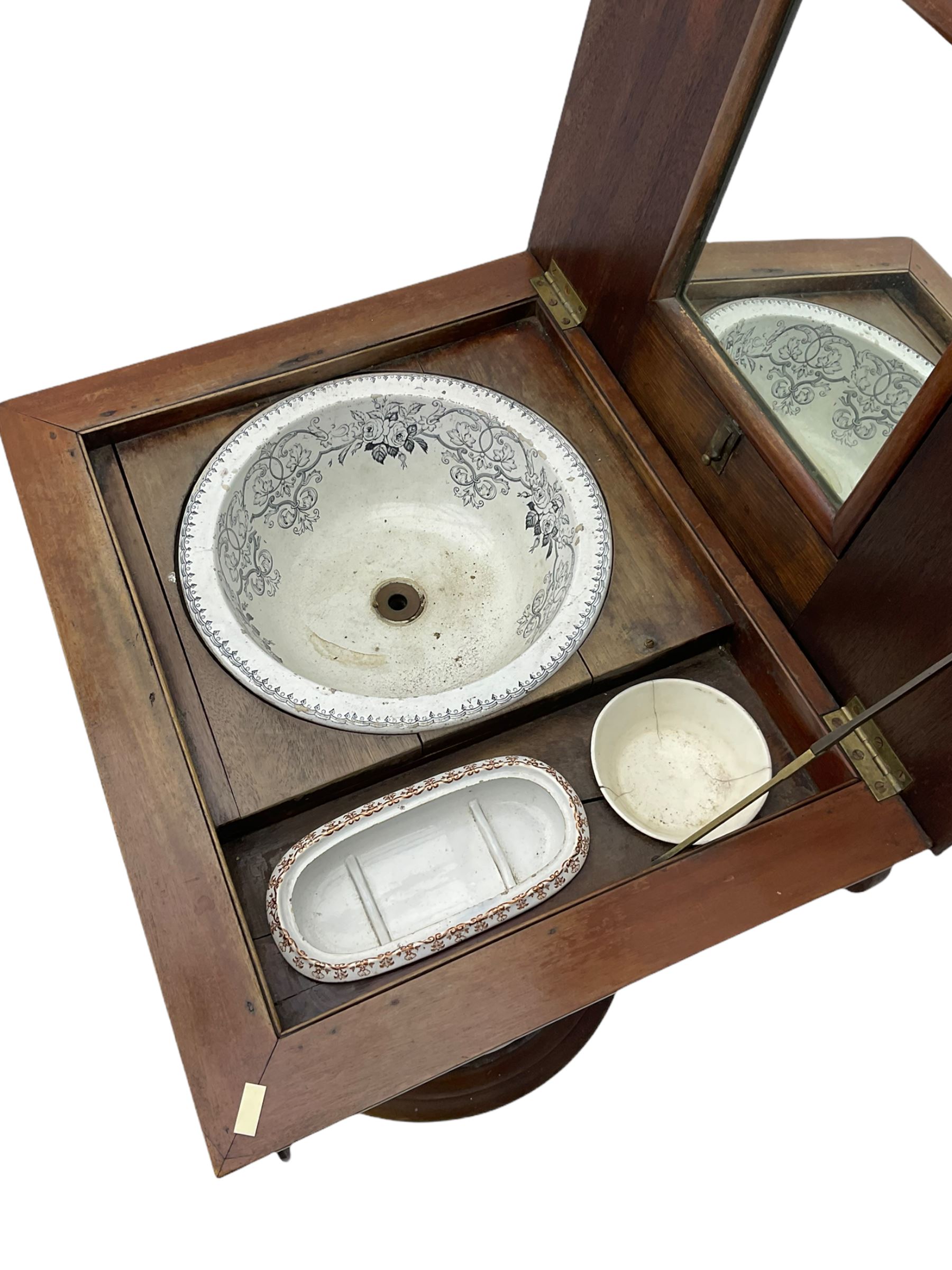 Victorian mahogany vanity unit in the form of a column, the scrolled top with hinged lid revealing mirror, wash bowl and toiletry dishes, on scalloped cylinder pedestal with single door, the interior fitted with shelf