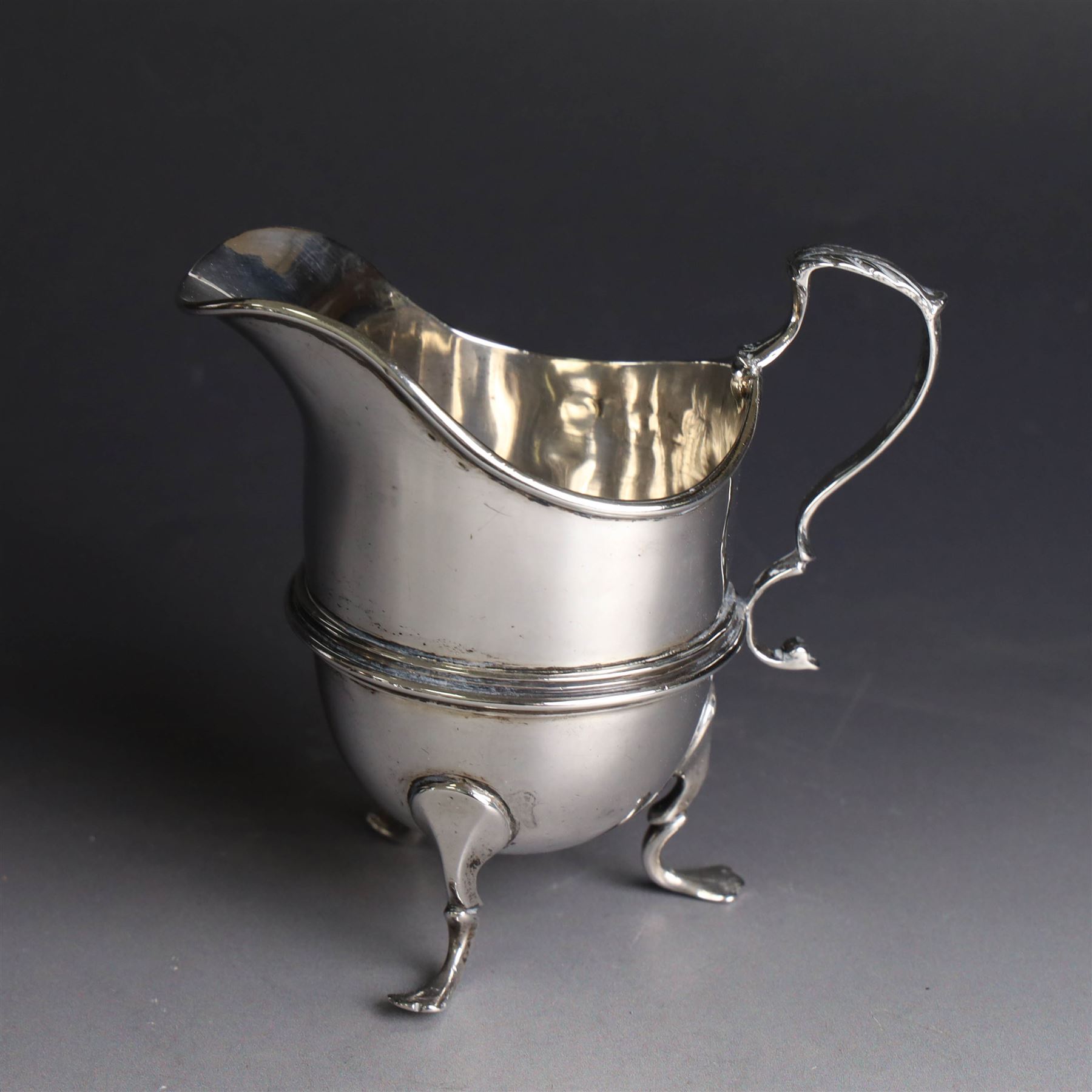 Late Victorian silver helmet shaped cream jug, with acanthus capped handle and upon three pad feet, hallmarked Birmingham 1898, maker's mark worn and indistinct, probably T Beardsmore, H10cm