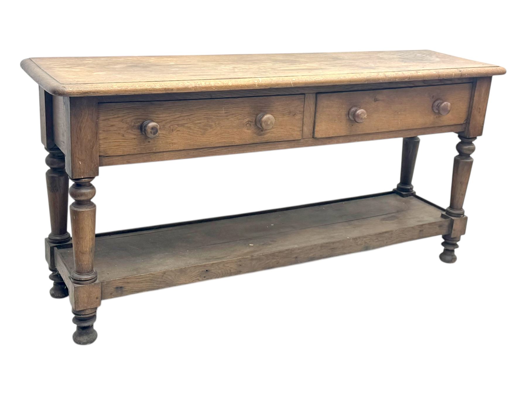 Late 19th century oak potboard dresser base, rectangular top over two frieze drawers with turned wooden handles, raised on four ring turned and tapering supports with block feet, united by a full-width lower potboard