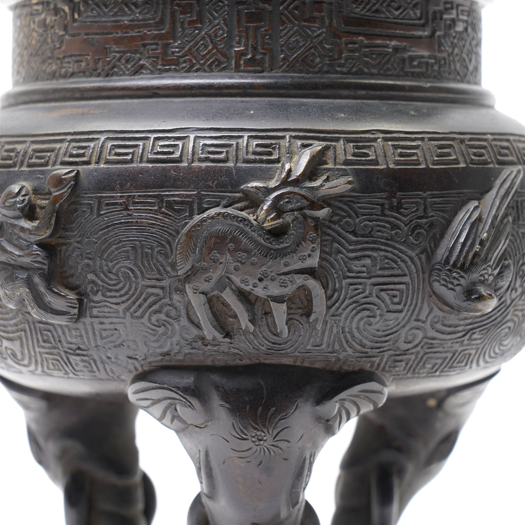 Early 19th century Chinese Qing Dynasty bronze censer, the body of globular form with circular neck and twin cast lion mask ring handles, decorated with applied figures of a monkey, deer and bird, against a key fret detailed ground, the whole upon three zoomorphic elephant feet, H16.4cm D12cm