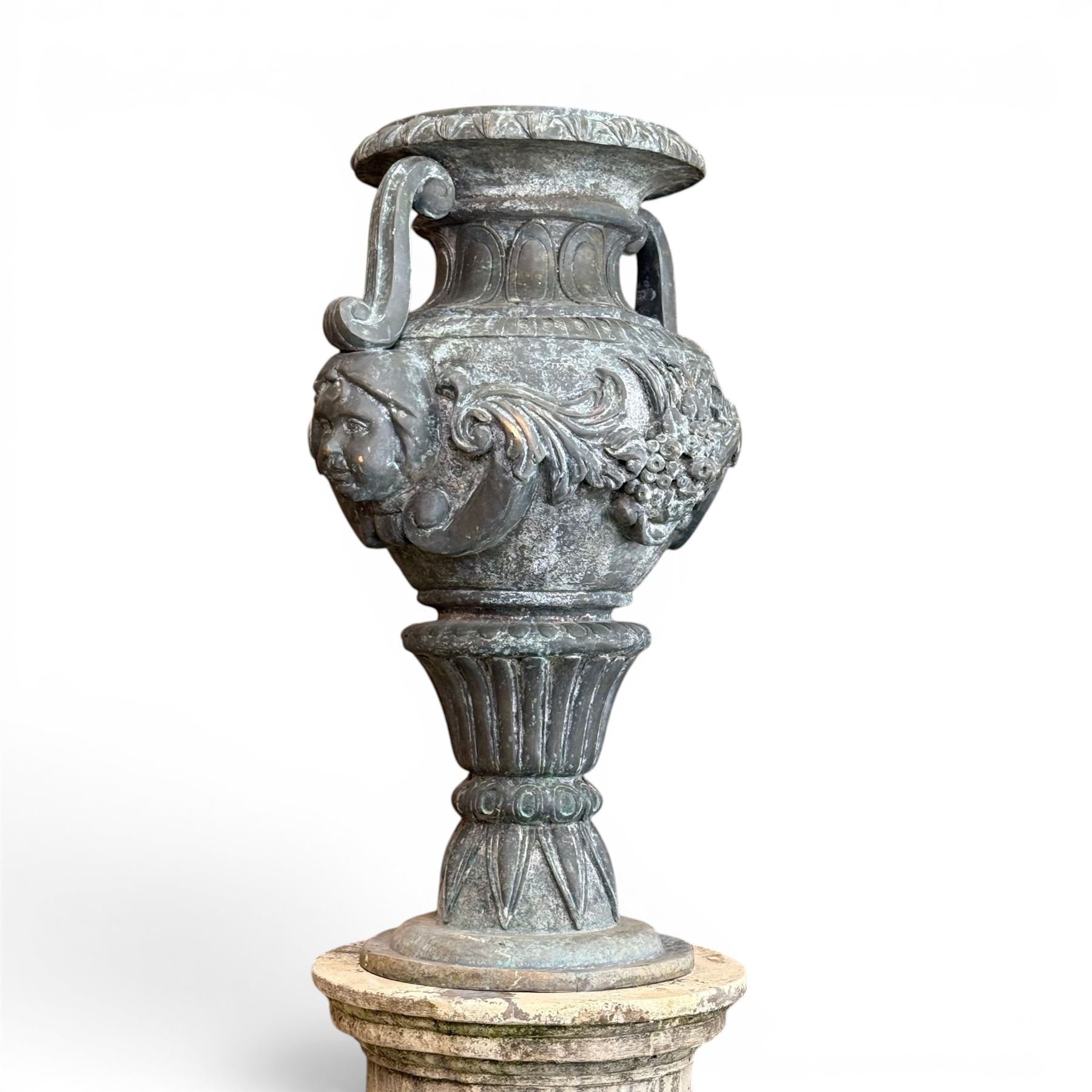 Large impressive Classical cast bronze center-piece urn, twin scroll handles with grape garlands, cherub masks and relief detail, raised on a circular cast stone pedestal with moulded detail