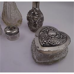 Two silver mounted dressing table jars, one in the form of a heart, both with embossed silver covers and cut glass bodies, hallmarked, together with two smaller examples, one set with mother of pearl, three silver mounted glass scent bottles, including an example with prunus blossom decoration, stamped Sterling, tallest bottle H17cm