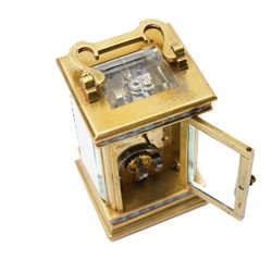 French- Edwardian miniature brass 8-day timepiece carriage clock with cloisonné panels to both base and cornice and paste gems to the front columns, decorative porcelain dial with a floral swag, blue Arabic numerals, minute track and pieced steel hands, square viewing glass to the top with a silvered lever escapement, with original leather bound traveling case.
