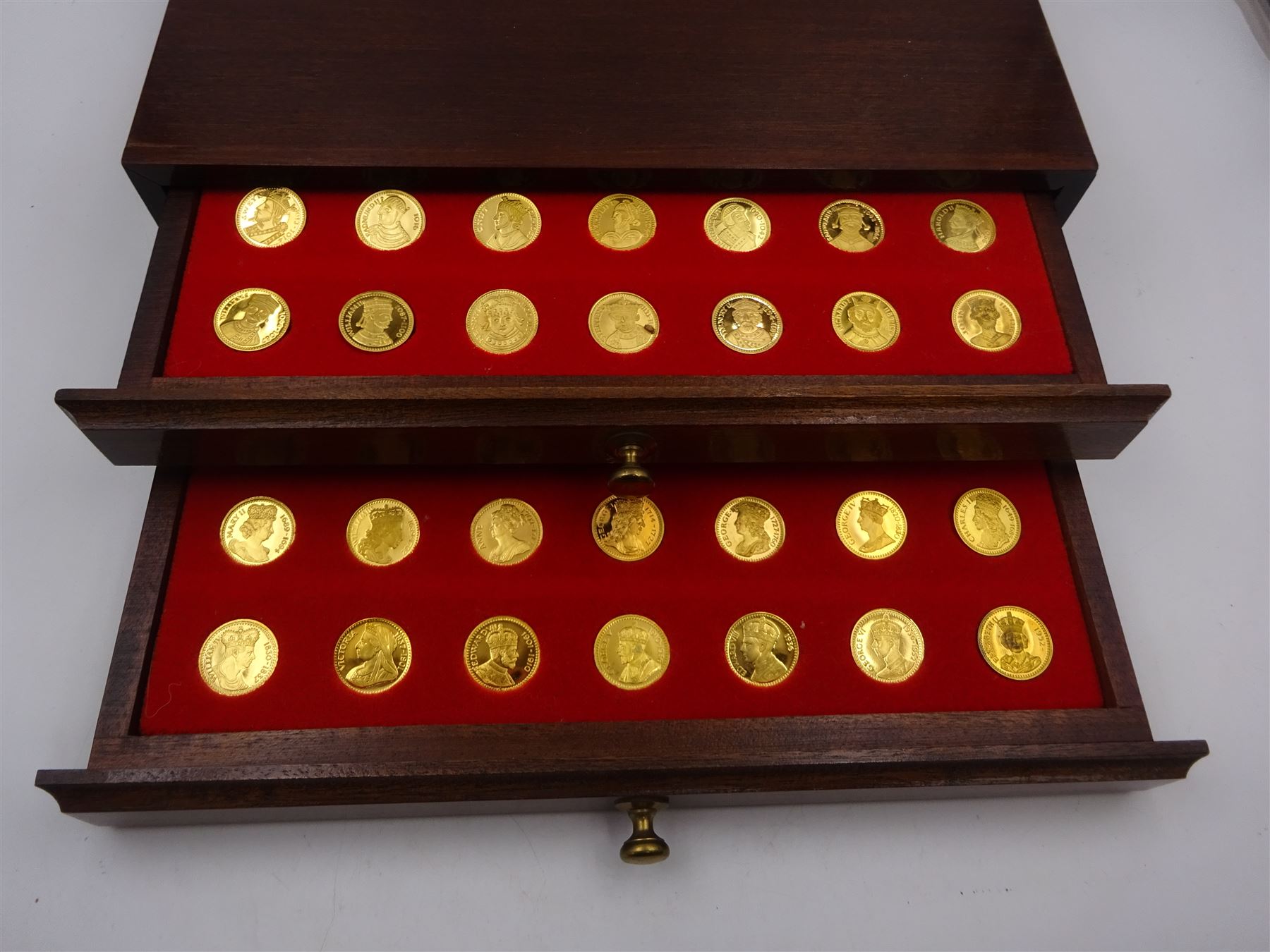 Danbury Mint, Our Royal Sovereigns Collection, seventy 22 carat gold plated silver medallions depicting the complete line of British monarchs to mark the 1200th anniversary of the first coronation, contained within wooden table top collectors cabinet with two drawers, with certificate of authenticity, with two drawers, hallmarked Danbury Mint, London various dates
