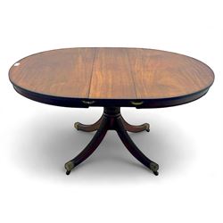 Regency design mahogany extending dining table, circular top with reeded edge and pull-out mechanism to accommodate additional leaf, raised on a carved central baluster column with acanthus detailing, supported by a quadruple reeded splay base terminating in brass caps and castors

