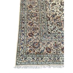 Persian Kashan ivory ground carpet, the field decorated with interlacing foliate branches and stylised plant motifs, scrolling border decorated with repeating palmettes, within floral pattern guard bands