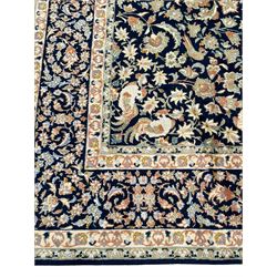 Persian Kashan indigo ground rug, the field consisting of trailing flower head bands and leafy branches, decorated with kuş or bird motifs, the border with repeating border containing curling leaves and flower heads, within guard bands 