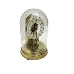  A late 20th century -  German Kieninger & Obergfell, “Kundo” battery operated
mantle clock under an acrylic shade, with an electrically operated solenoid pendulum housed on a circular brass base, skeleton movement with visible motion work through a painted 4-1/2” open chapter ring, with pierced steel hands, Roman numerals and minute track.
