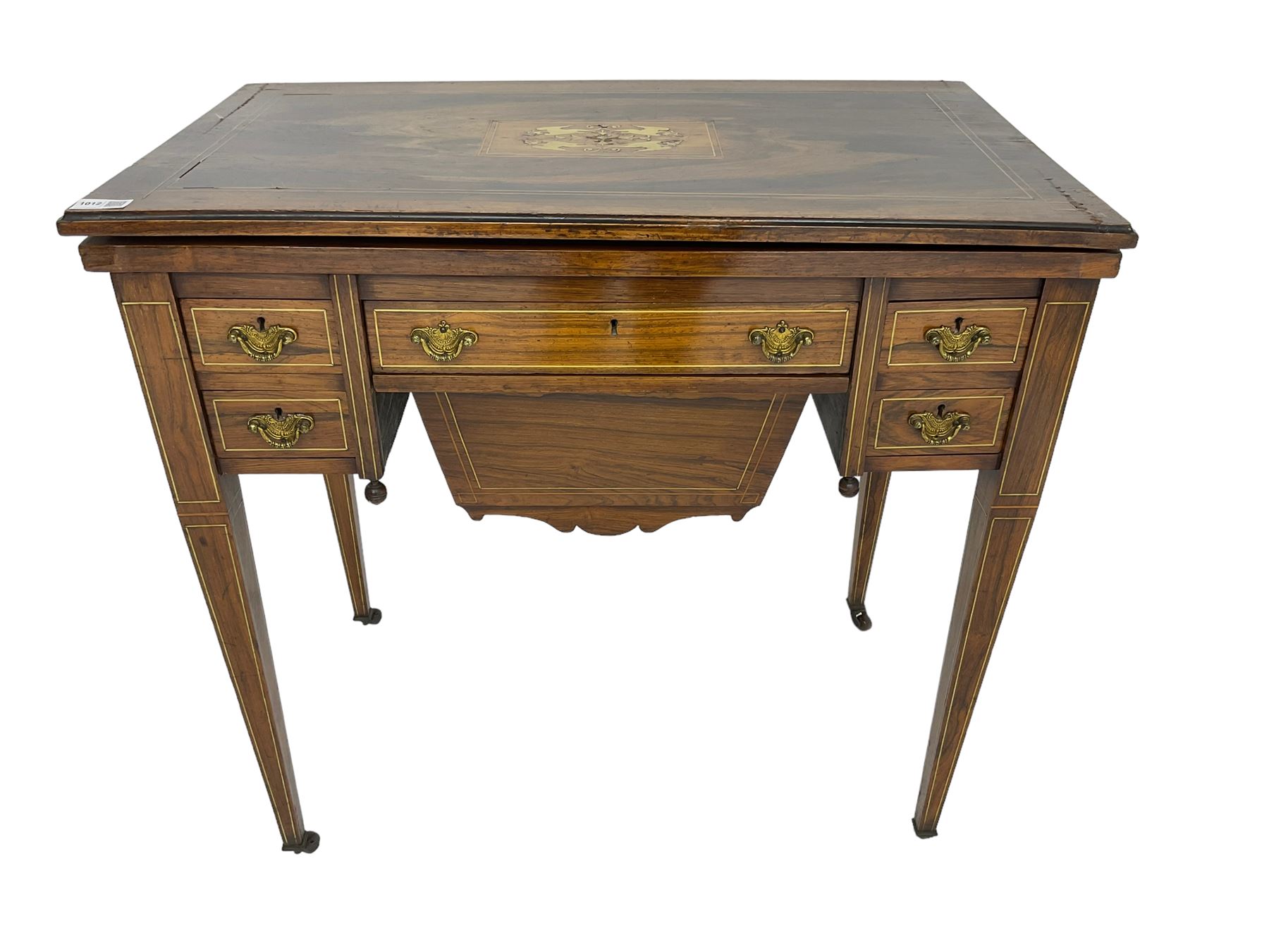 Edwardian inlaid mahogany games or work table, rectangular fold-over top inlaid with stylised dragon ivorine decoration and stringing, fitted with one long flanked by four small drawers over sewing compartment drawer, raised on square tapering supports with castors