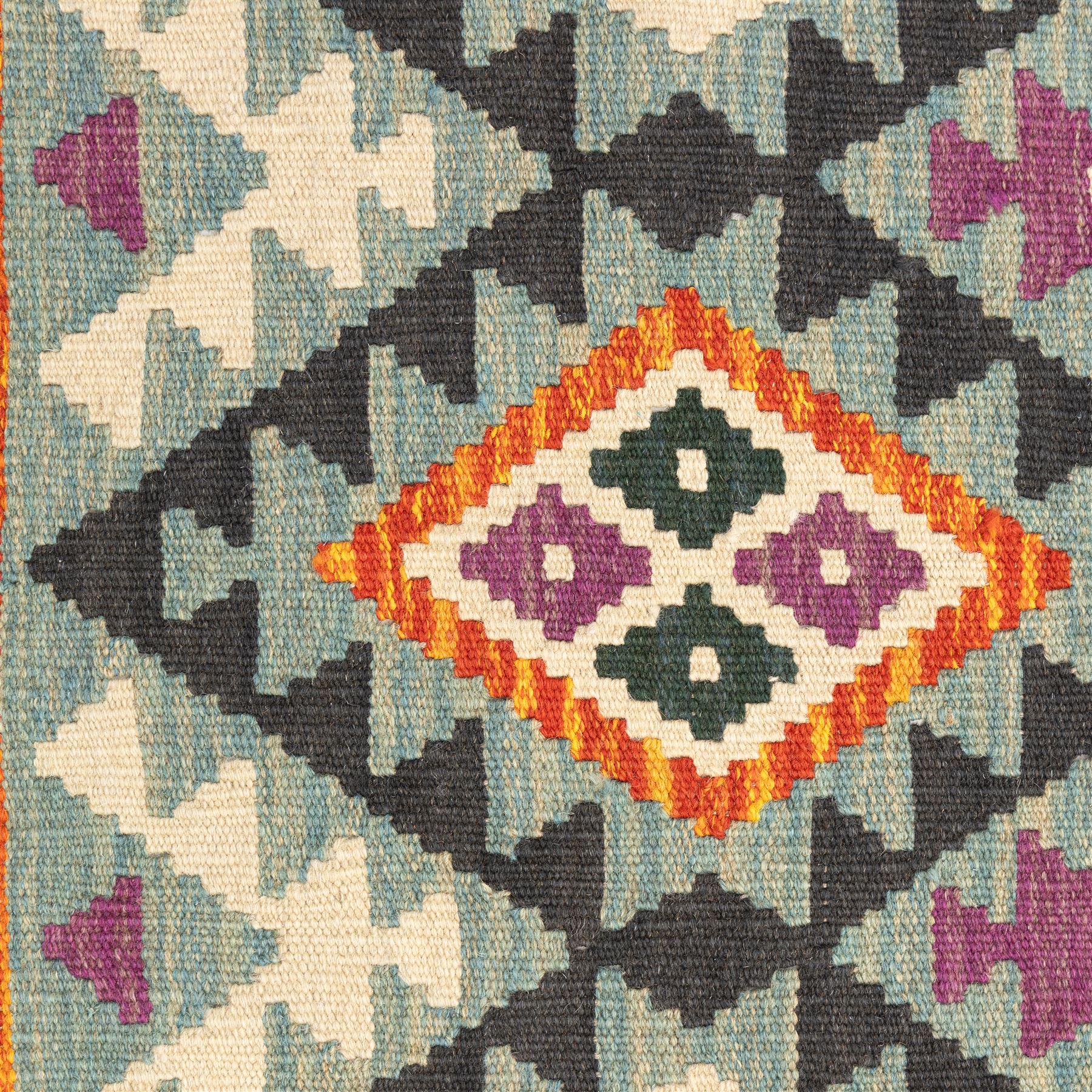 Chobi flatweave kilim runner with a repeating stepped diamond medallion design in live green, rust, teal, purple, and ivory, framed by chevron and geometric borders