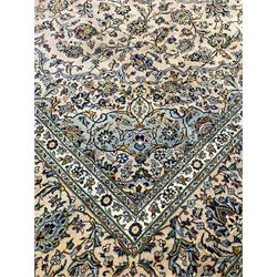 Central Persian Kashan pale khaki ground carpet, shaped central medallion enclosing small stylised motifs, the field decorated profusely with trailing foliate branches and plant motifs, guarded border with repeating floral design 