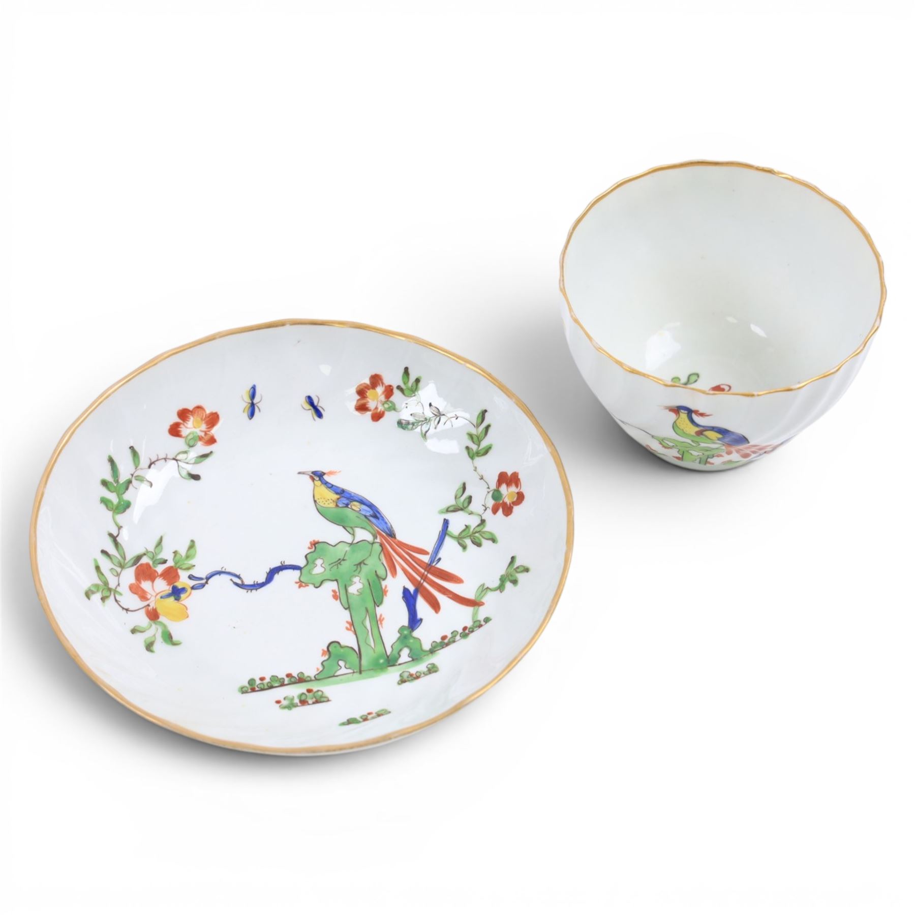 Chamberlain's Worcester teabowl and saucer, each of wrythen form decorated in the Sir Joshua Reynolds pattern, circa 1800, with long tailed Ho Ho bird perched upon green rockwork and surrounded by flowering vines, the saucer with iron red pattern number 203 beneath, teabowl H6cm D8.5cm, saucer D14cm