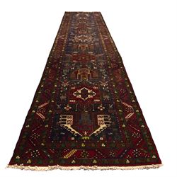 Large Northwestern Persian Hamadan hand-knotted runner, indigo field, with a column of bold geometric medallions and scattered stylized motifs within a madder border of angular rosettes and meandering vines 