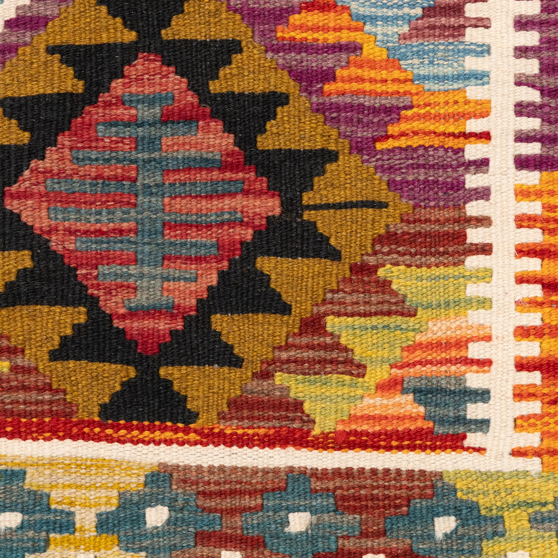 Afghan kilim rug, the field in earthy tones decorated with columns of repeating lozenges with further geometric motifs, the teal guard band with repeating stepped lozenges heightened with ivory