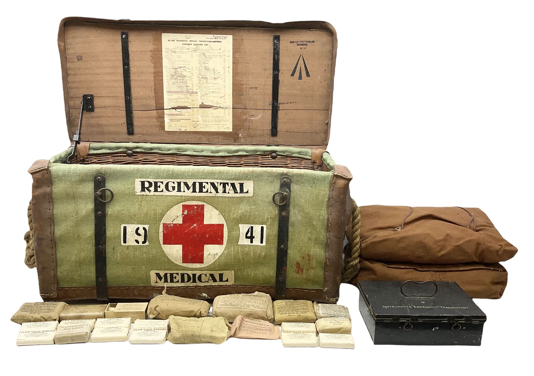 WW2 British Army RAMC 'Regimental Medical Pannier', well marked externally and dated 1941, stamped May 1943 internally, canvas covered wicker form with leather edges, hinged top and fall front with two rope carrying handles, fitted iron locking straps with securing chains; contains various unused field dressings and bandages with WW2 dates and two pillows; original label under lid L79cm