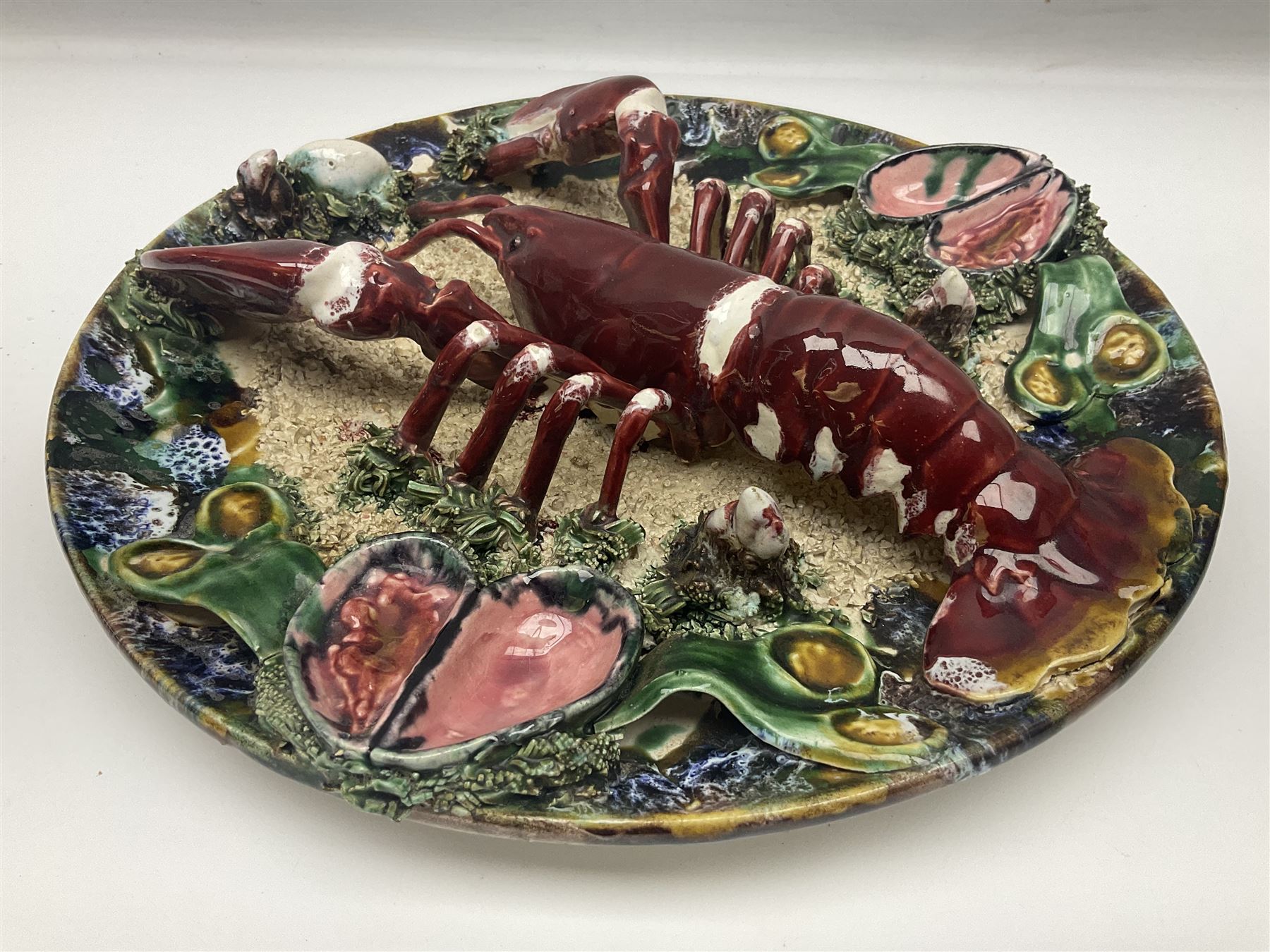 Two 20th Century Portuguese Palissy style Majolica wall plates, one depicting a crab, the other a lobster each to the centre modelled in relief surrounded by encrustations and shells, both with impress marks beneath, D34cm