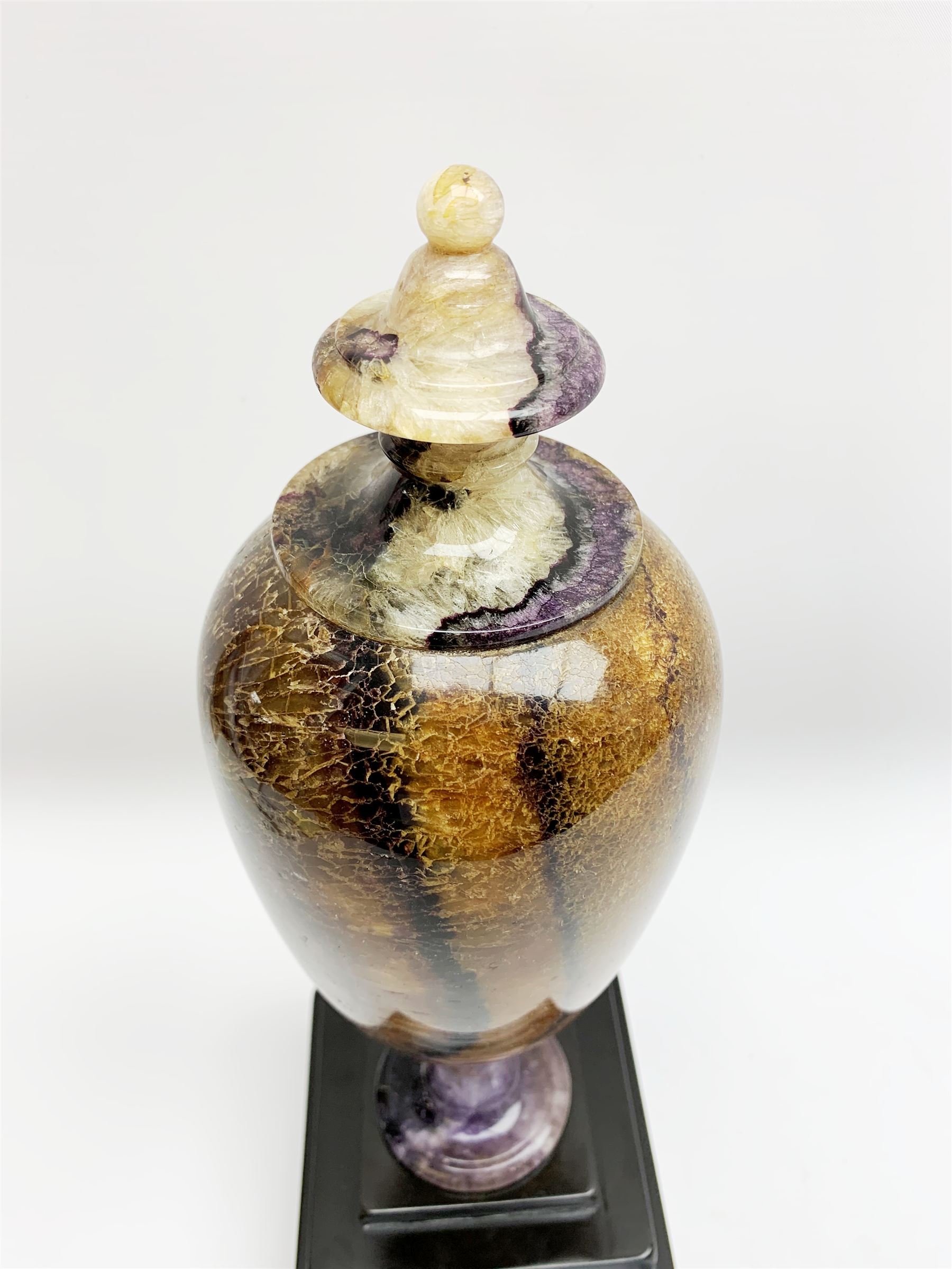 Early 19th century and later Blue John urn, Winnats one vein, of ovoid form with integrated cover and ball finial, upon a spreading circular base, and square stepped black lacquered base, H34.5cm