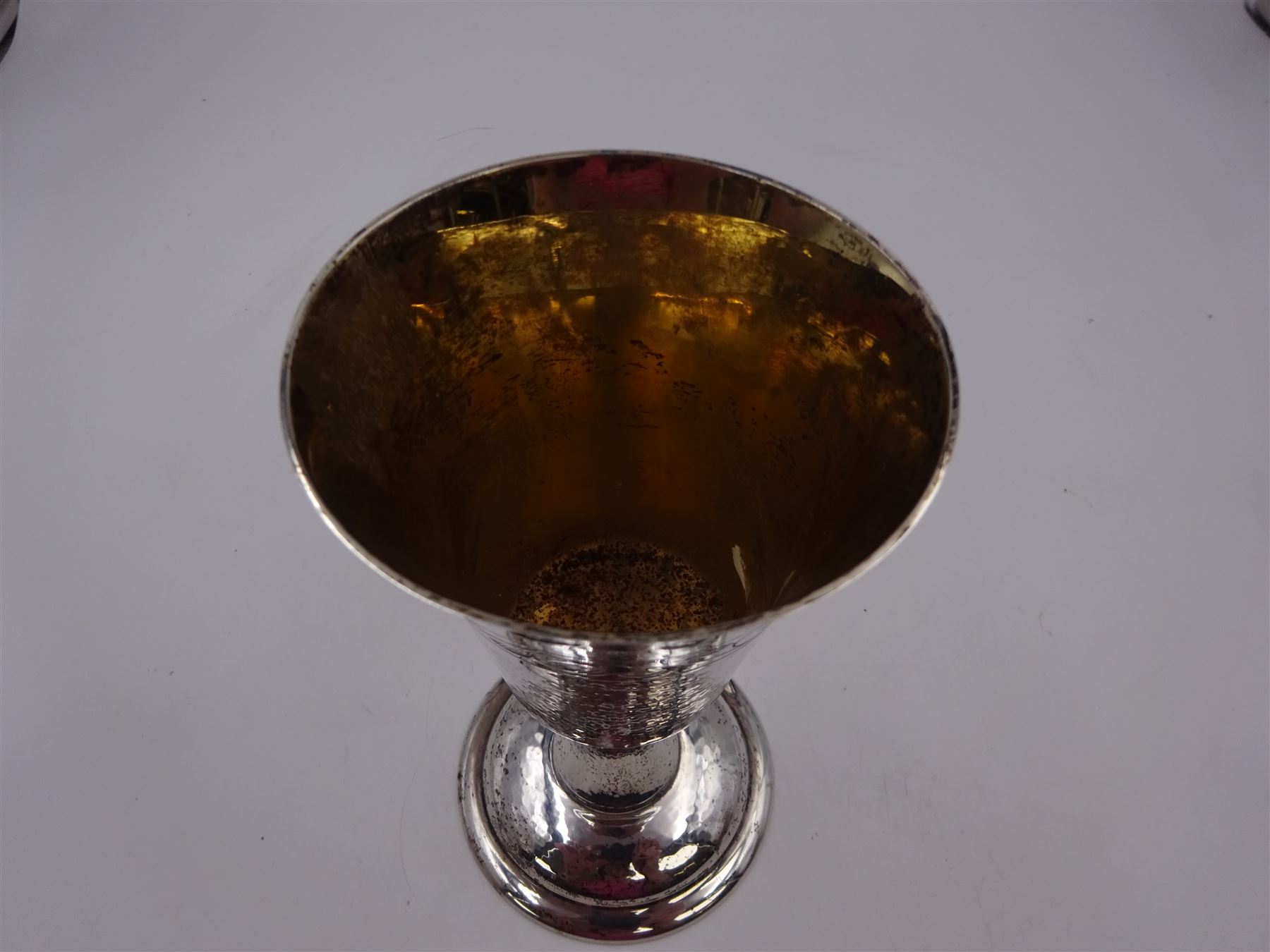 Modern limited edition silver goblet, a replica of the original silver chalice of Lincoln Cathedral, with hand planished decoration, and engraved band of laurel leaves to bowl, with gilt interior, upon waisted stem and circular stepped foot, no. 144/200, hallmarked John Cussell, London 1977, H15cm