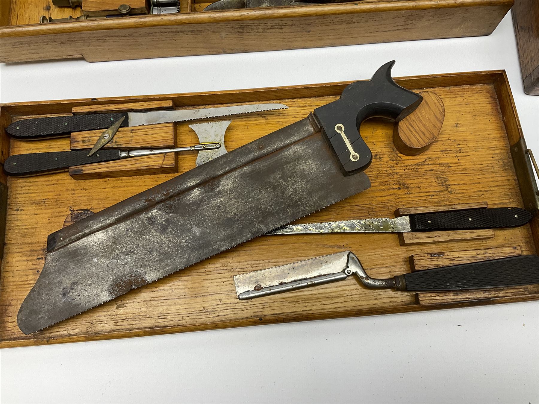 Naval doctor's surgical instruments, contained in a converted brass bound oak pistol box, the hinged lid opening to reveal two removable fitted trays, containing 19th century and later saws, scalpels, tweezers etc