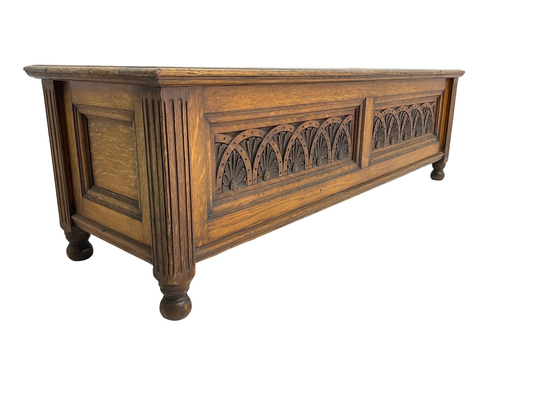 Early 20th century oak ‘bay window’ shaped blanket chest or coffer, hinged top, the front with two lunette carved panels flanked by fluted uprights, on turned feet