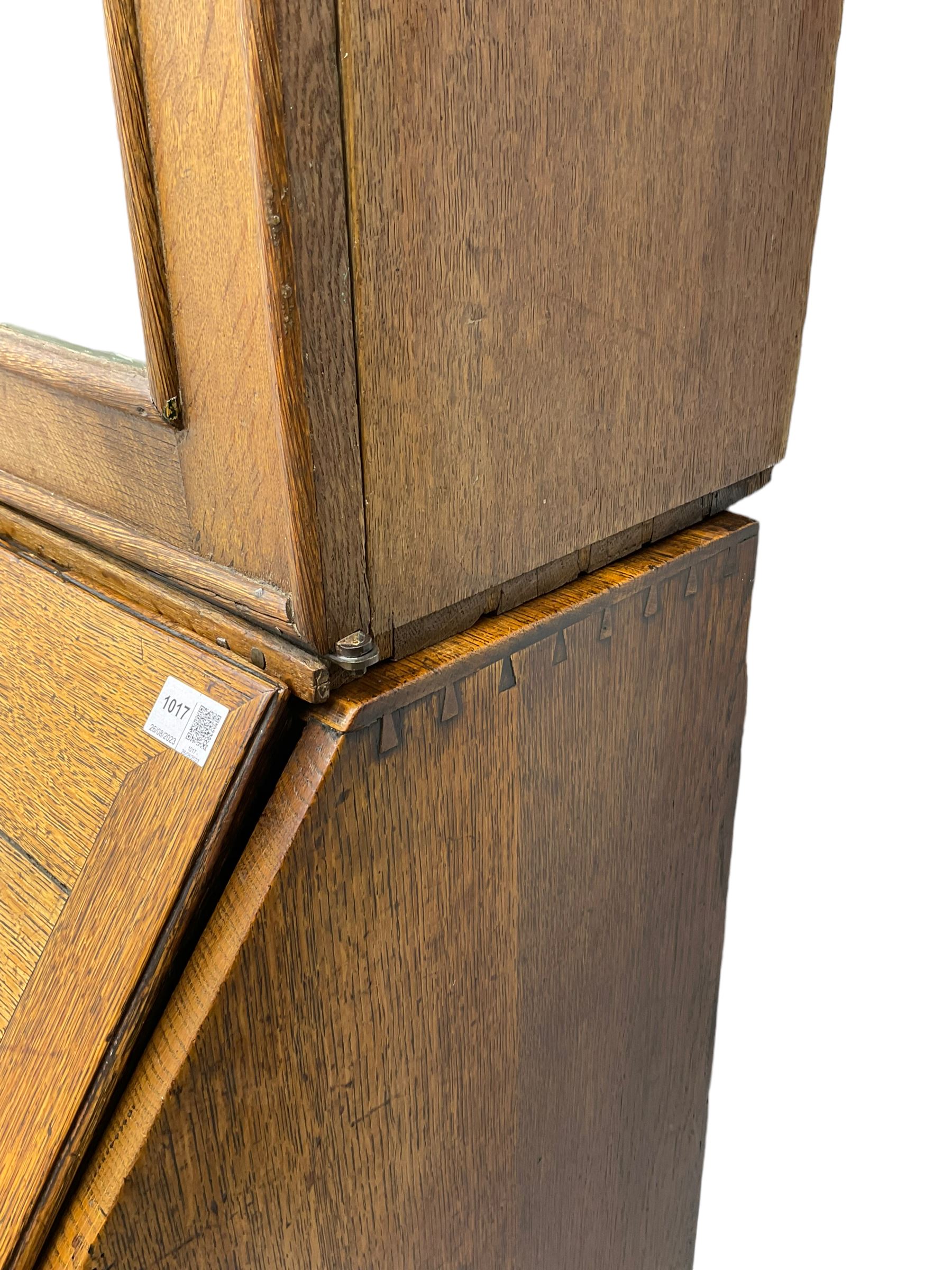 George III oak bookcase on bureau, the double arched top enclosed by two shaped glazed doors, fall-front concealing fitted interior, over four graduating cock-beaded drawers, on bracket feet