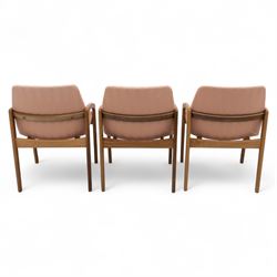 Mid-20th century Danish teak armchairs, each with curved open arms and upholstered seat and backrest in salmon pink striped fabric, raised on tapering legs