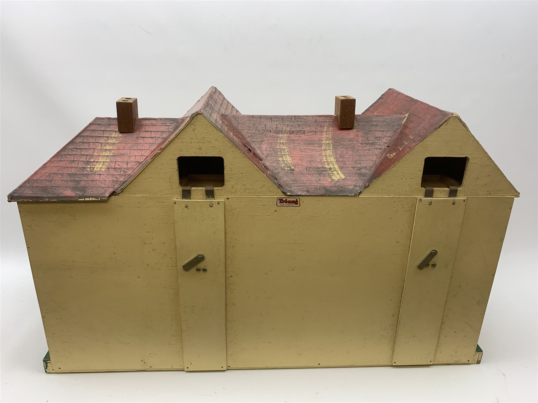 1950s Tri-ang large wooden doll's house of double fronted Tudor style with painted faux stucco walls, simulated tiled pitched roof and opening tin-plate windows, the double hinged front opening to reveal four rooms on two floors with staircase and landing and integral garage, wired for electric lighting L86cm D31cm H50cm; together with large quantity of well-made wooden furniture for lounge, dining room, kitchen, bedrooms and bathroom (bath labelled Dol-Toi), three dolls, household accessories and plastic table wares etc