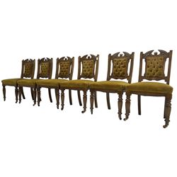 Set of six late Victorian carved oak dining chairs, buttoned back and sprung seat upholstered in mustard yellow velvet, on turned front supports with castors