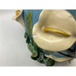 George Jones style majolica jardiniere of globular form, supported on four feet formed from modelled lily leaves growing up the side of the pot, with swallows flying amongst the white lily flowers, all set against a blue ground, with a pink interior, H27cm