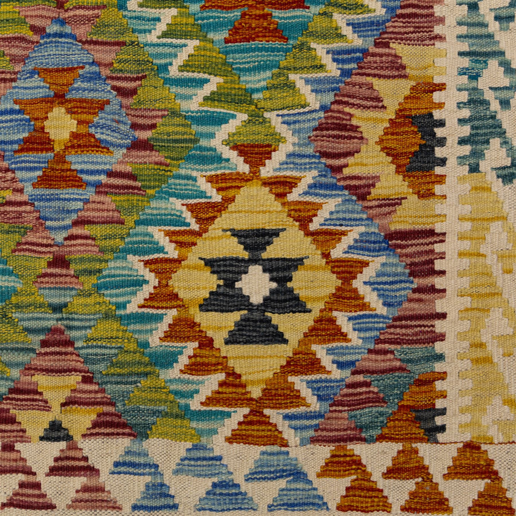 Chobi flatweave kilim with a repeating stepped diamond medallion design in live green, rust, teal, purple, and ivory, framed by chevron and geometric borders