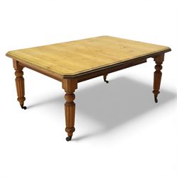 Early 20th century stripped pine kitchen table, the rectangular planked top with moulded edge and canted corners, upon stained pine turned and fluted legs with castors