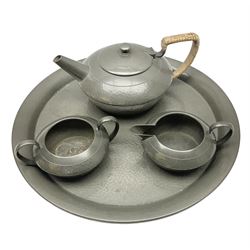 Liberty & Co Tudric pewter three piece tea service, comprising teapot with woven reed handle, twin handled open sucrier, and milk jug, each of squat form with planished finish, each impressed beneath Tudric Pewter Ware 01537 Made in England, together with a matched unmarked tray